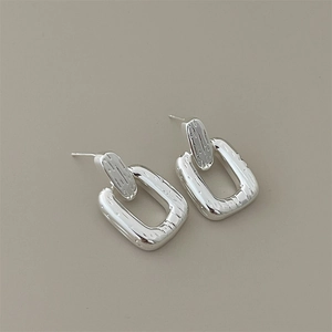 Close-up of minimalist geometric rectangular silver earrings with a polished finish