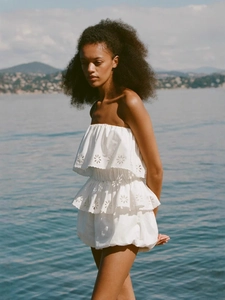 Close-up of white cotton midi dress featuring intricate hollow embroidery and wavy hem