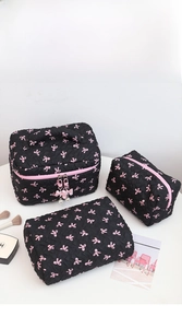 Three-piece black quilted makeup bag set with pink bows and pearl zipper detail