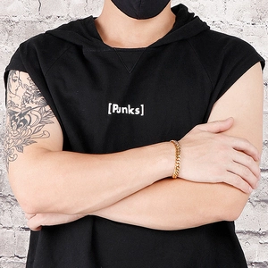 Gros plan d'un bracelet gourmette doré avec fermoir OT au poignet d'un homme style punk