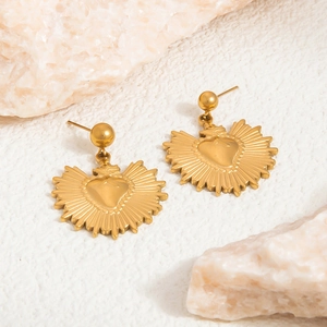 Macro shot of 18K gold plated heart sun earrings on textured white background with stones