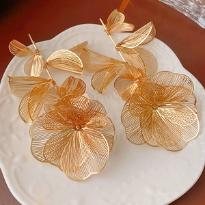 Close-up of golden hollow flower earrings with delicate metal silk floral details