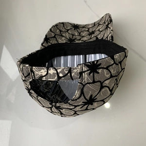 Detail view of floral lace baseball cap with metal buckle and breathable mesh fabric