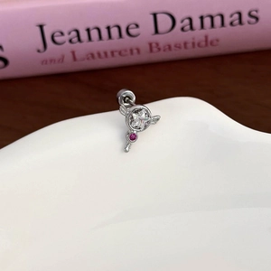 Macro view of silver star and red zircon stud earring on a wavy white stand