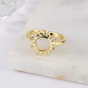 Adjustable sun-shaped gold plated ring with cubic zirconia on white marble base