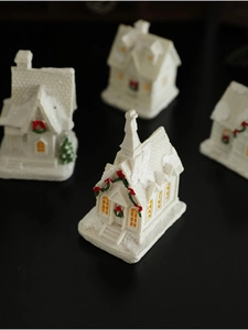 Macro view of white resin Christmas cottages with LED lights and festive snow coating