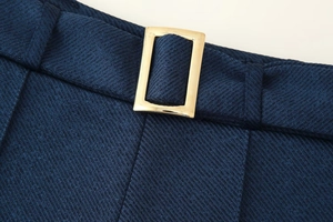 Détail du tissu sergé bleu marine avec une boucle décorative en métal doré rectangulaire