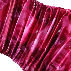 Close-up of fuchsia satin fabric with ruched texture and shimmering sequins detail