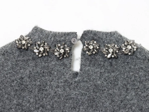 Dettaglio di maglieria in mohair grigio con fiori di strass e chiusura posteriore a bottone