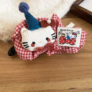Detailed view of red plaid bow hair clip with white plush cat and party hat detail