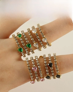Macro detail of multi-layered 18k gold rings with heart-shaped colorful zircons