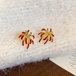 Boucles d'oreilles feux d'artifice rouges plaquées or avec strass sur fond peluche