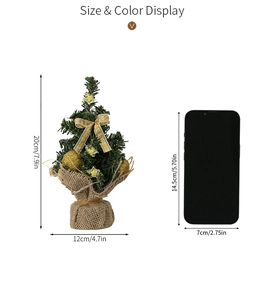 Mini lighted Christmas tree with gold ornaments and burlap base next to a phone for scale