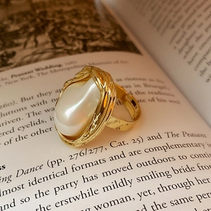 Détail d'une bague dorée irrégulière avec perle sur un fond de livre artistique élégant