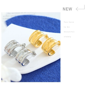 Close-up of gold and silver C-shaped earrings with wide curved design on stone