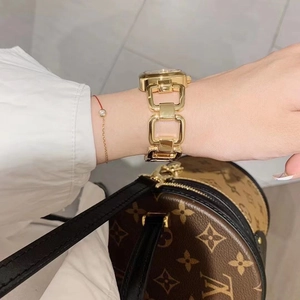 Close-up of elegant gold square watch with chain strap and red string on wrist