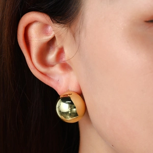 Polished 18K gold-plated spherical stud earring on model with glossy geometric design