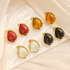 Detail of four pairs of teardrop resin earrings in red, amber, black, and clear colors