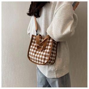Detail of checkered knit canvas crossbody bag with adjustable brown strap on a model