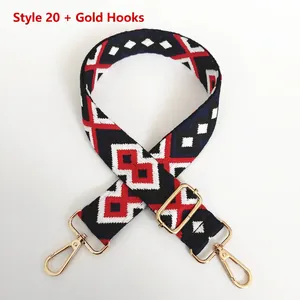 Detail of adjustable canvas bag strap with red and black geometric jacquard and gold hooks