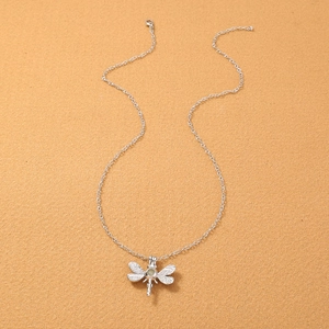 Collana libellula vintage in argento con ciondolo a perla luminosa su fondo in legno
