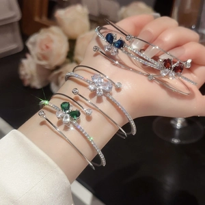 Dettaglio di bracciali a farfalla in zircone con pietre a goccia di vari colori