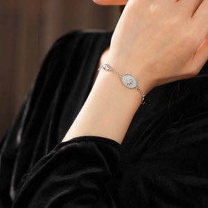Close-up of a silver starburst oval pendant bracelet on wrist with black velvet sleeve