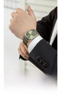 Close-up of olive green leather strap watch with silver oval case on male wrist