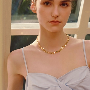 Elegant gold choker necklace with heart sequins worn by a model in soft light