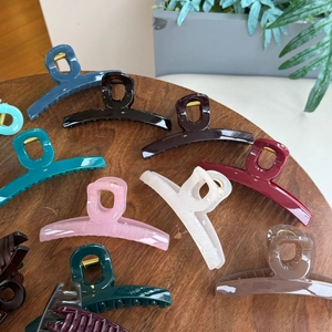 Close-up of assorted large butterfly hair claws in various glossy colors on wooden surface
