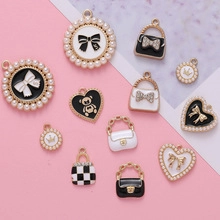 Flat lay view of DIY jewelry charms including heart and handbag shapes in gold and enamel