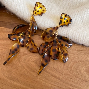 Macro shot of tortoiseshell acrylic petal earrings with leopard print and silver pins