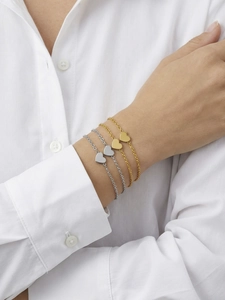 Detail shot of heart pendant thin chain bracelets in gold and silver on a white shirt