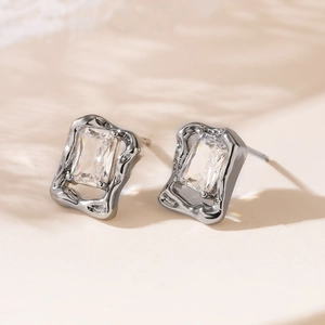 Macro detail of silver geometric stud earrings with rectangular zircon in lava texture