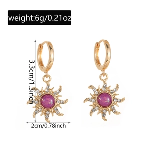 Detail of gold sunburst earrings with purple stone and white crystals showing 3.3cm length