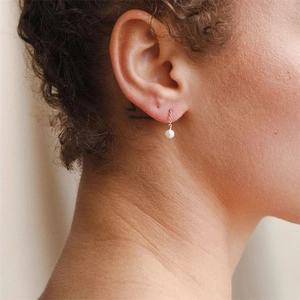 Gros plan d'une boucle d'oreille en perle d'eau douce sur chaîne dorée au style élégant