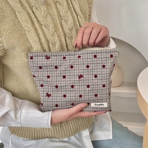 Dettaglio della trousse in cotone a scacchi con pois rossi e ricamo a fiocco elegante