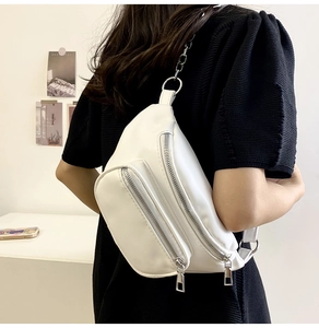 Side view of white PU leather crossbody chest bag with silver chain strap on model