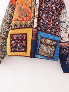 Detailed close-up of colorful patchwork floral quilted jacket with orange and blue patterns