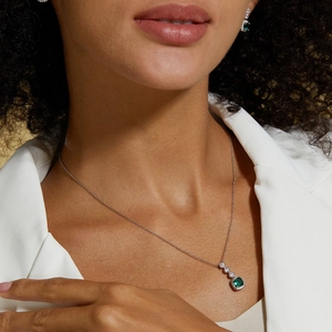 Close-up of elegant S925 silver necklace featuring emerald green gemstone and zircon details