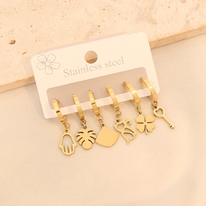 Détail de six boucles d'oreilles en acier inoxydable doré avec charms Hamsa et feuilles