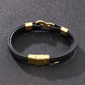 Detail of black braided leather bracelet with golden infinity symbol and secure metal clasp
