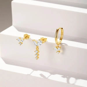 Detailed view of S925 silver gold earrings with white zircon leaf charms on white stands