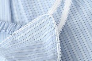 Close-up of blue vertical stripe fabric with delicate white lace trim and ruffled strap detail