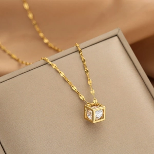 Macro shot of gold cube pendant with cubic zirconia on a wave chain jewelry box detail