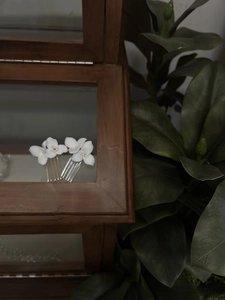 Detailed close-up of white ceramic flower and pearl hair comb with gold-tone metal teeth
