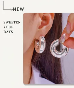Detailed close-up of chunky silver C-shaped earrings with a polished mirror finish on model