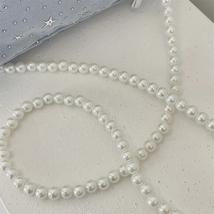 Close-up of light blue canvas tote bag with pearl chain and silver star rhinestone detail