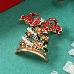 Detail view of a golden Christmas bell brooch with red bow and pearl accents