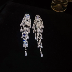 Détail de boucles d'oreilles pendantes à pompons argentés avec strass étincelants